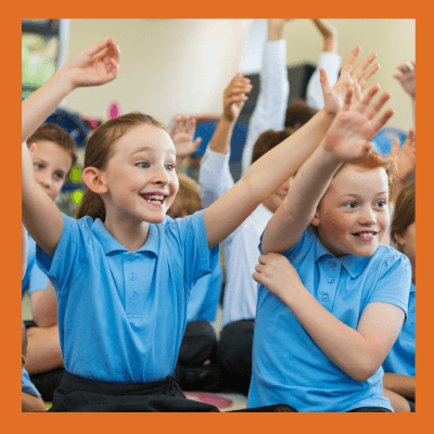 Children in classroom raising hands