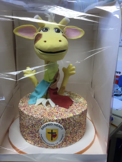 A cake with Harold the giraffe on top