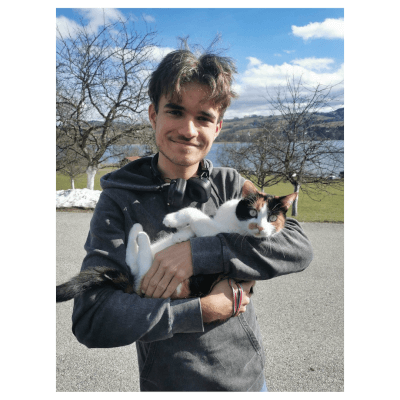 Young man smiling whilst holding a cat