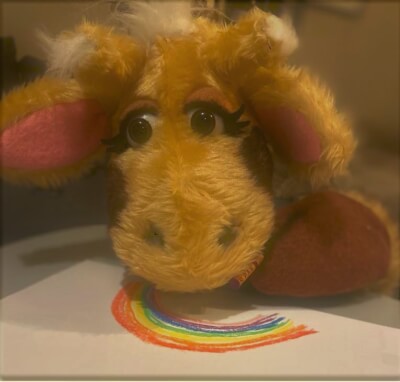 Harold the giraffe drawing a rainbow with coloured pastels