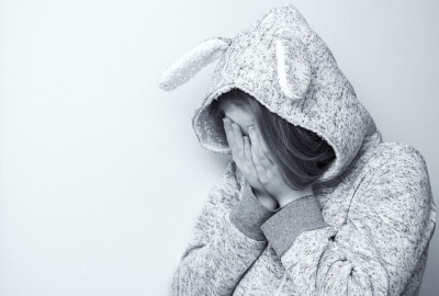 black and white photograph of an upset female child with her head in her hands